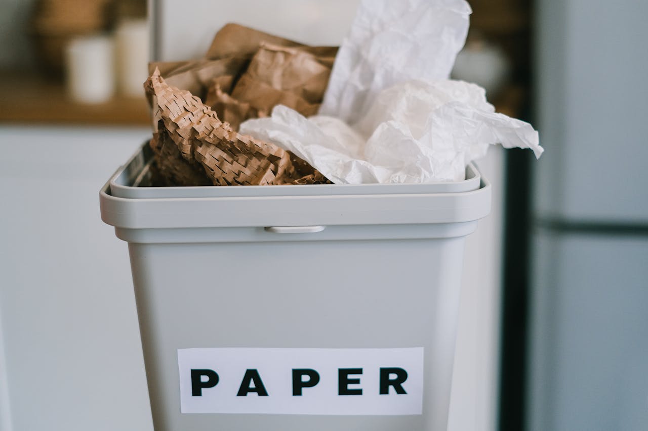Closeup of plastic container full of paper placed on blurred background of kitchen in daytime